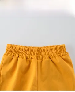 Detail of yellow kids shorts featuring a high-elastic pleated waistband and textured fabric