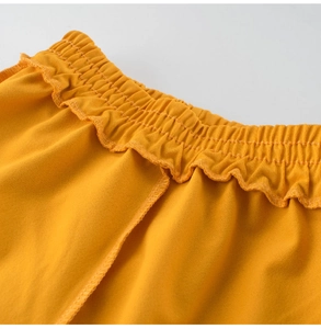 Detail of yellow quick-dry shorts featuring an elastic waist and ruffled edges texture