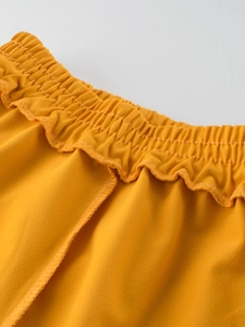 Kids quick-dry summer shorts featuring mustard yellow paperbag elastic waist and ruffle trim