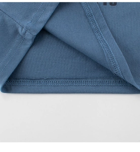 Détail de la couture double et de la texture sur l'ourlet du t-shirt bleu pour enfant