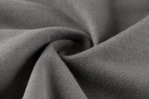 Dettaglio del tessuto in cotone grigio lavorato a maglia con texture morbida e traspirante