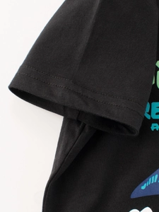 Gros plan sur la manche d'un T-shirt noir en coton avec double couture et motif dinosaure