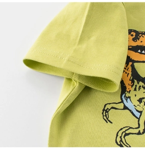 Gros plan sur la couture de la manche d'un t-shirt enfant vert en coton dinosaure