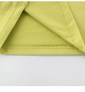 Détail de la double couture sur l'ourlet du t-shirt vert en coton pour enfant, tissu doux