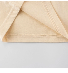 Macro detail of fine double-needle hem stitching on soft apricot cotton kids' t-shirt