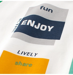 Close-up of white cotton T-shirt fabric featuring colorful geometric prints and ENJOY text