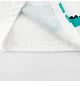 Detailed close-up of double-stitched hem on a white cotton T-shirt with dinosaur print