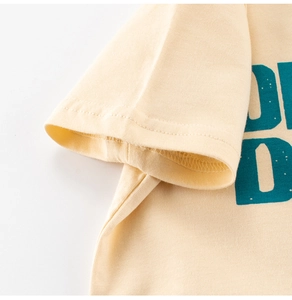 Detail von blaugrünem Buchstabendruck und Doppelnadelstich auf beige Baumwollshirt