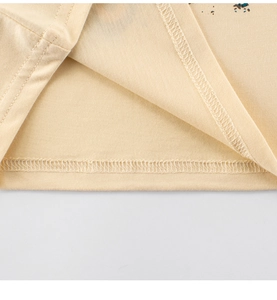 Nahaufnahme der Overlock-Naht am Saum eines beigefarbenen Baumwoll-T-Shirts für Jungen