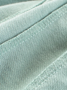 Vue macro du tissu en tricot vert menthe montrant la qualité des coutures overlock