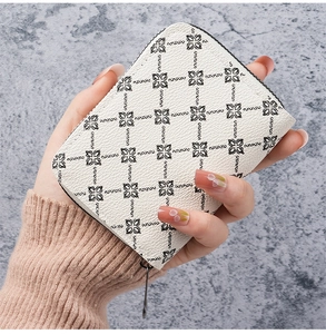 Close-up of cream leather card holder with black floral pattern and side zipper detail