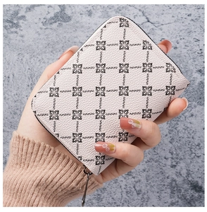 Handheld view of a cream leather card holder with floral print and silver zipper detail