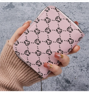 Close-up of pink faux leather card holder with black swan print held in hand