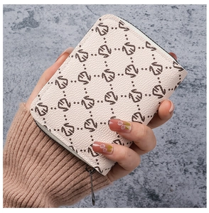 Handheld view of a cream monogrammed card holder wallet with textured faux leather finish