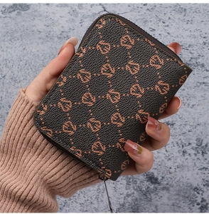 Close-up of a brown monogram card holder with zipper closure in textured faux leather