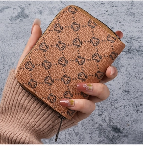 Close-up of tan lychee grain leather card holder with all-over logo print and zipper
