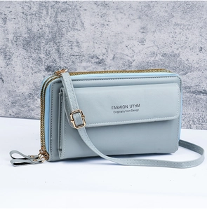 Detail of light blue crossbody bag with double gold zippers and front flap pocket