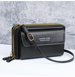 Close-up of black leather crossbody bag featuring triple zippers and gold metal hardware