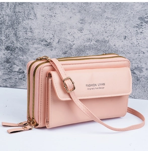 Side view of pale pink crossbody bag showing three compartments and gold metal zippers