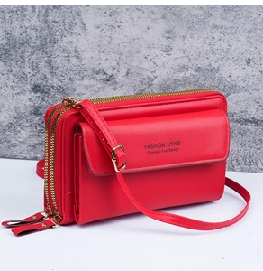 Detail view of red leather crossbody bag featuring dual zippers and front flap pocket