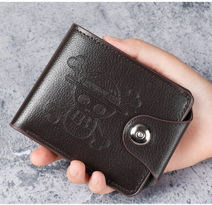 Detail of bifold brown wallet with pebbled leather texture and pirate logo button