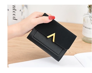 Close-up of black patchwork wallet with golden V-metal clasp held by a hand