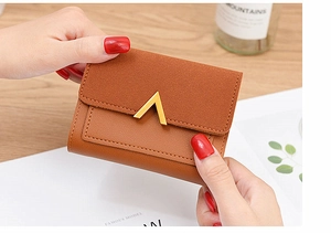Close-up of caramel leather short wallet featuring vintage V-shaped golden metal clasp