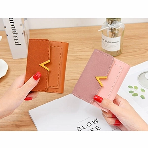 Detailed close-up of compact bi-fold wallets with textured leather and gold V-shaped metal buckle