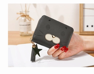 Close-up of a dark grey cartoon cat wallet with litchi grain texture and tassel charm