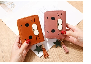 Close-up of cute cartoon cat-themed short wallets in pink and orange with bow details