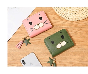 Close-up of cute cartoon seal zip wallets with star pendant and tassel on wooden desk