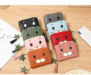 Flat lay of colorful cartoon seal print PU leather wallets with tassels on wooden desk