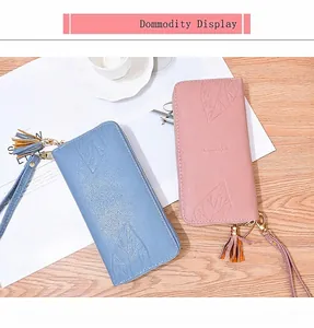 Detailed view of long zip wallets in pink and blue PU leather with leaf pattern and tassels