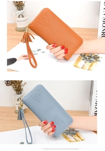 Detail of long women's wallet with maple leaf embossing and tassel in orange and blue