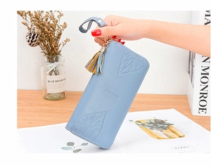 Close-up of sky blue leather wallet featuring maple leaf embossing and gold tassel
