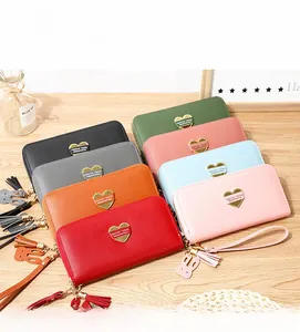 Close-up of heart-shaped metal logo and tassel charms on colorful long leather wallets