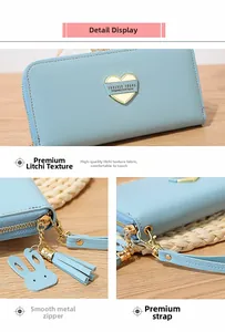 Detail of light blue pebble leather long wallet with heart plaque and tassel charm