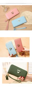 Detail of long leather wallets with heart hardware and elegant tassel charms in soft colors