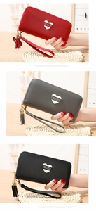 Close-up of litchi grain leather wallets with heart hardware and decorative tassels