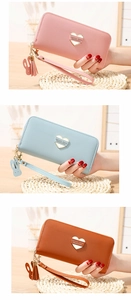 Close-up of heart metal hardware and tassel charm on long leather wallets in various colors