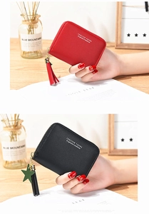 Detail of zip closure and tassel charm on litchi grain faux leather small wallet