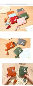 Détail de broderie florale sur portefeuille en cuir PU grainé avec pompon et breloque fleur