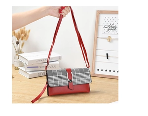 Detalle de bolso bandolera de cuero rojo con solapa de pata de gallo y hebilla de metal