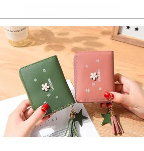 Close-up of floral zip wallets in pink and green with elegant tassel and star charms