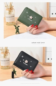 Detail view of mini flower zipper wallet with tassel star pendant and leather texture
