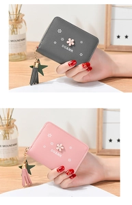 Detail of floral zipper wallets with leather tassels and star charms in pink and grey