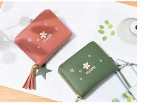 Detail of floral zipper wallets with leather tassels in green and dusty rose