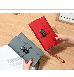 Detail of red and grey lychee leather clutch wallets with metal buckles and wrist straps