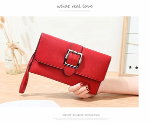 Detail of red litchi grain leather clutch bag featuring a large square metal buckle