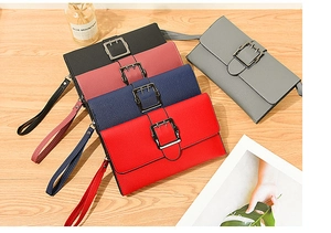 Detailed view of long litchi grain leather wallets with wristlets and metal buckle detail